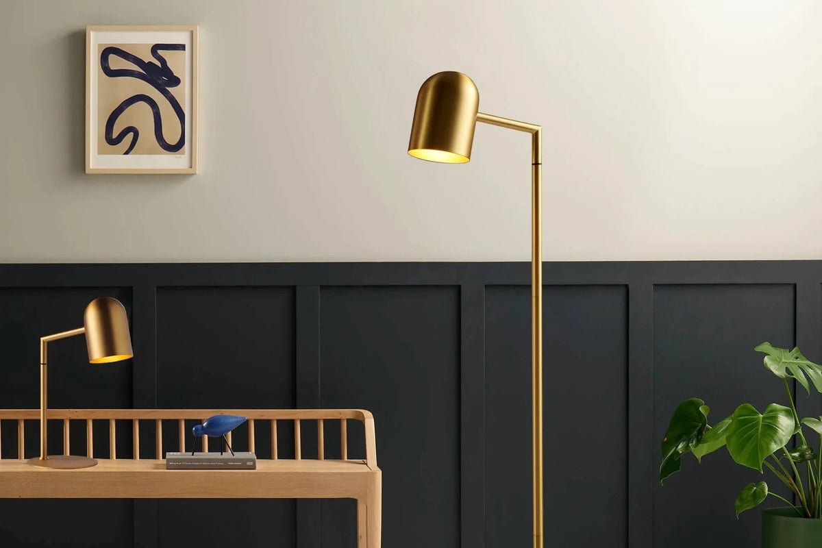 Gold floor lamp in a room with a desk and plant. Floor and desk lamp. Chrome or metal lamp. Reading or study light.