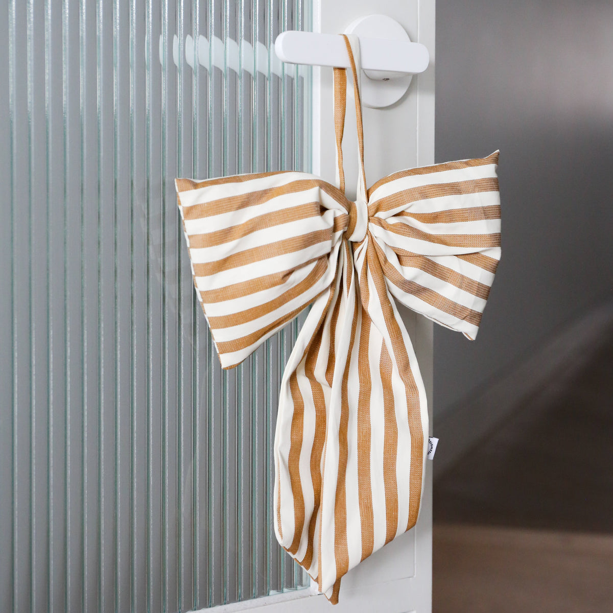 Brown and white striped bow on a white hanger against a neutral background