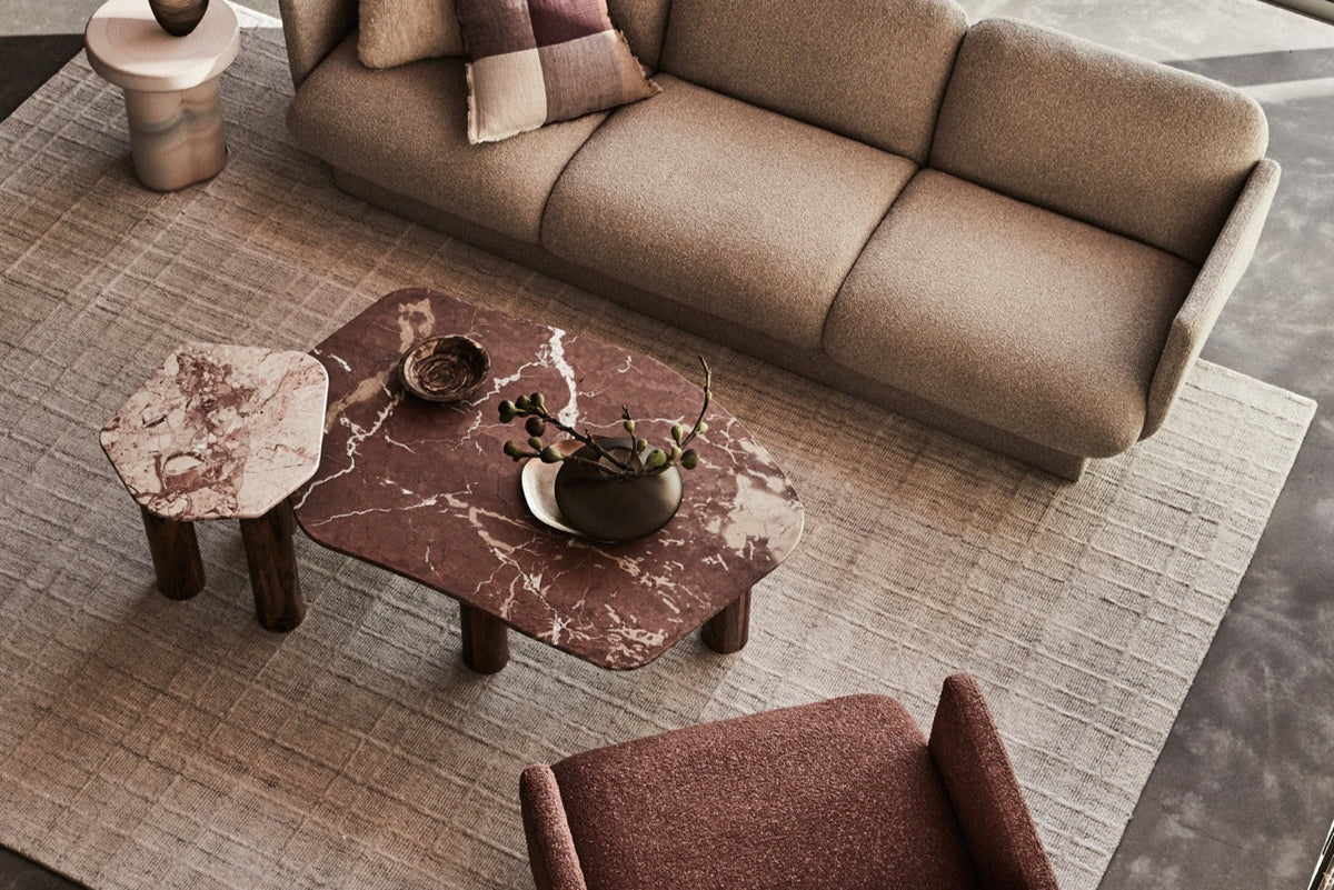 Modern living room with a beige sofa, marble coffee table, and brown armchair. Marble table. Side table styling 