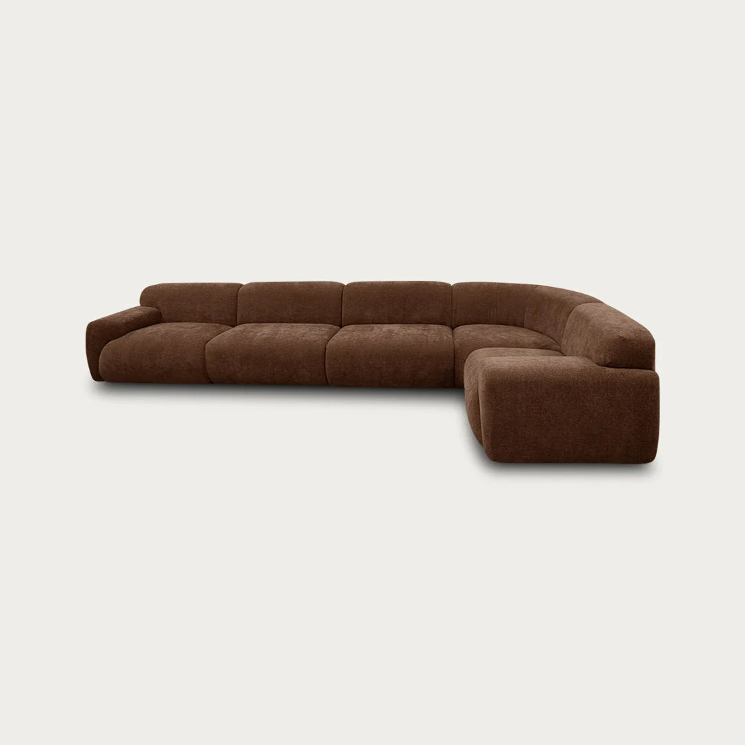 A curved brown upholstered sectional sofa with a chaise lounge attachment, shown against a plain off-white background.
