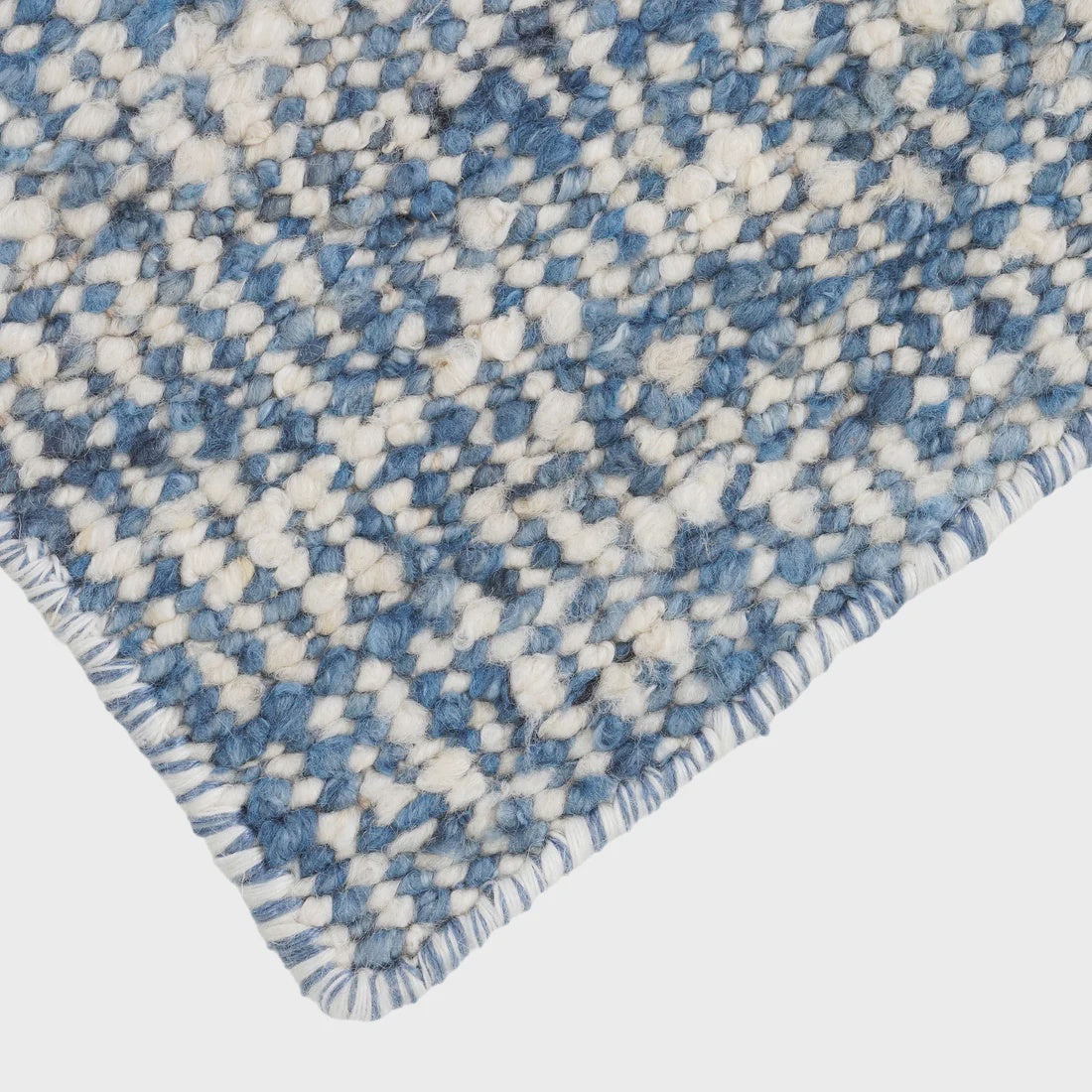 Close-up of a blue and white textured rug corner