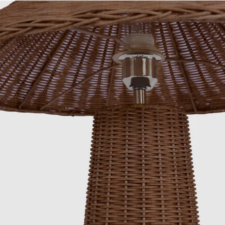 Close-up of a brown woven wicker patio umbrella or table umbrella base with a central metal fixture and light socket, shown against a plain light gray background.