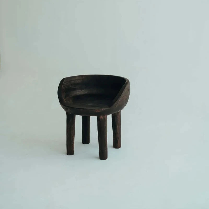 Carlos Chair in Walnut, carved rounded seat and backrest on three timber legs, shown on a white background.