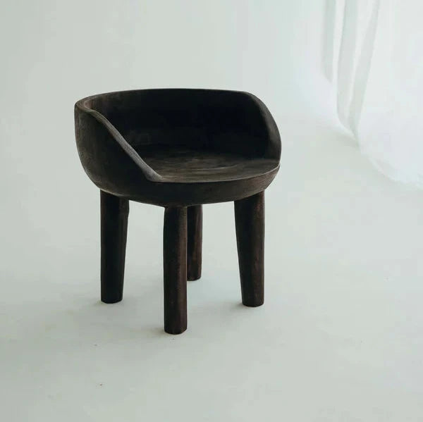 Carlos Chair in Walnut, carved rounded seat and backrest on three timber legs, shown on a white background.