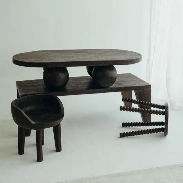 Carmen Stool in Walnut suar wood, round top on beaded bobbin-style legs, styled with its coordinating pieces.