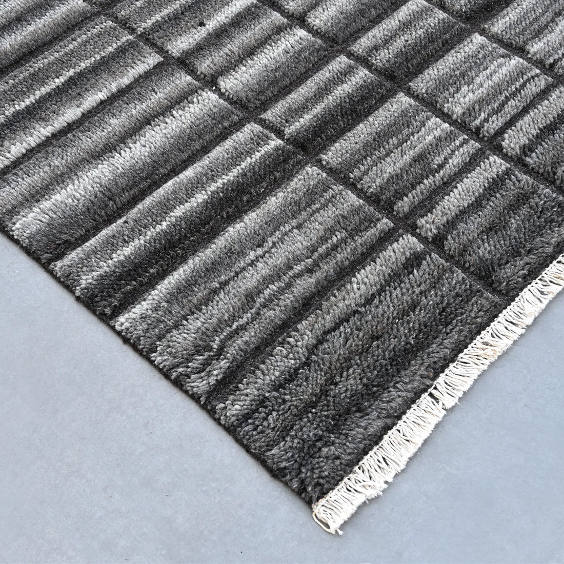 Gray textured rug with a linear pattern on a light gray background