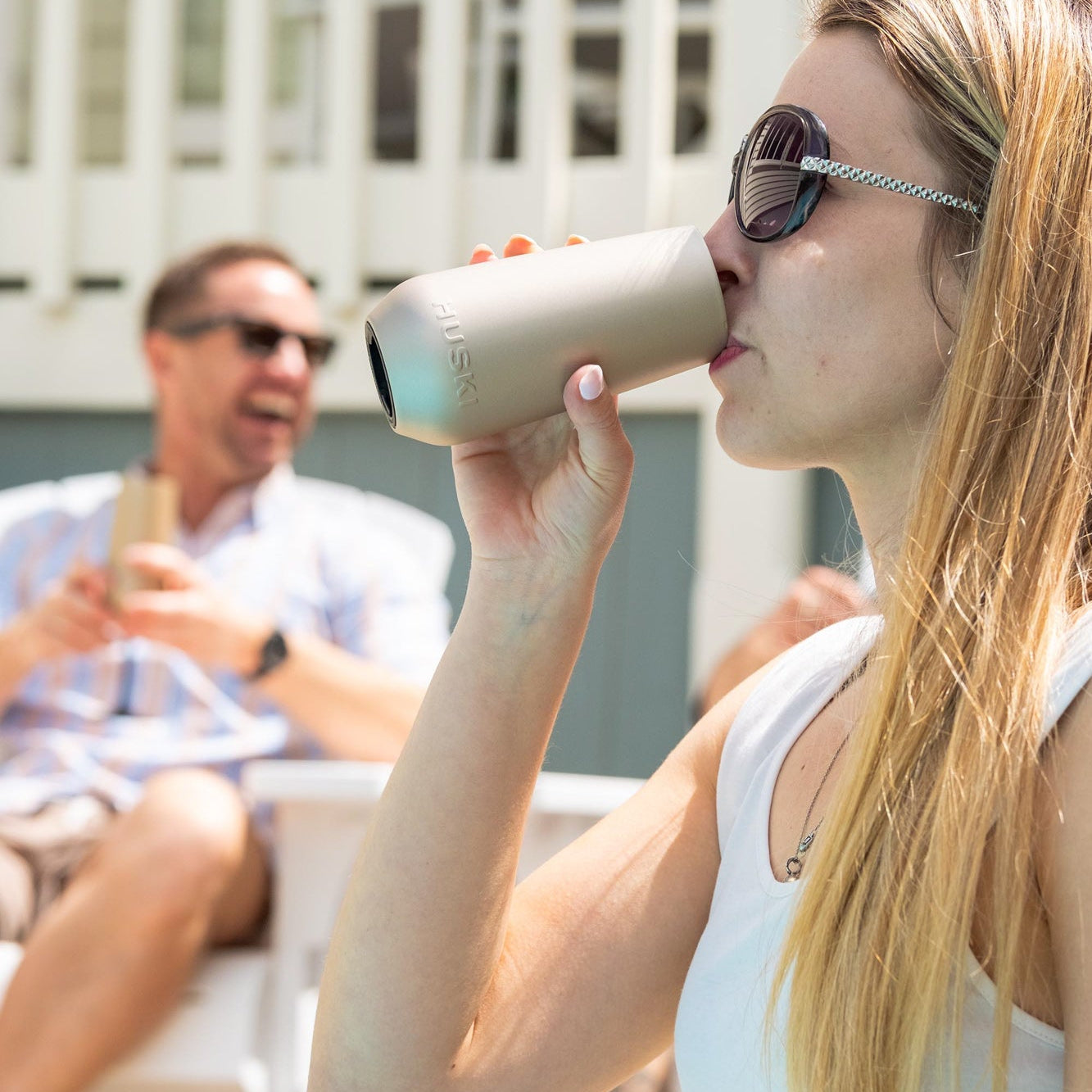 Woman drinking from a beige cup outdoors with a blurred background