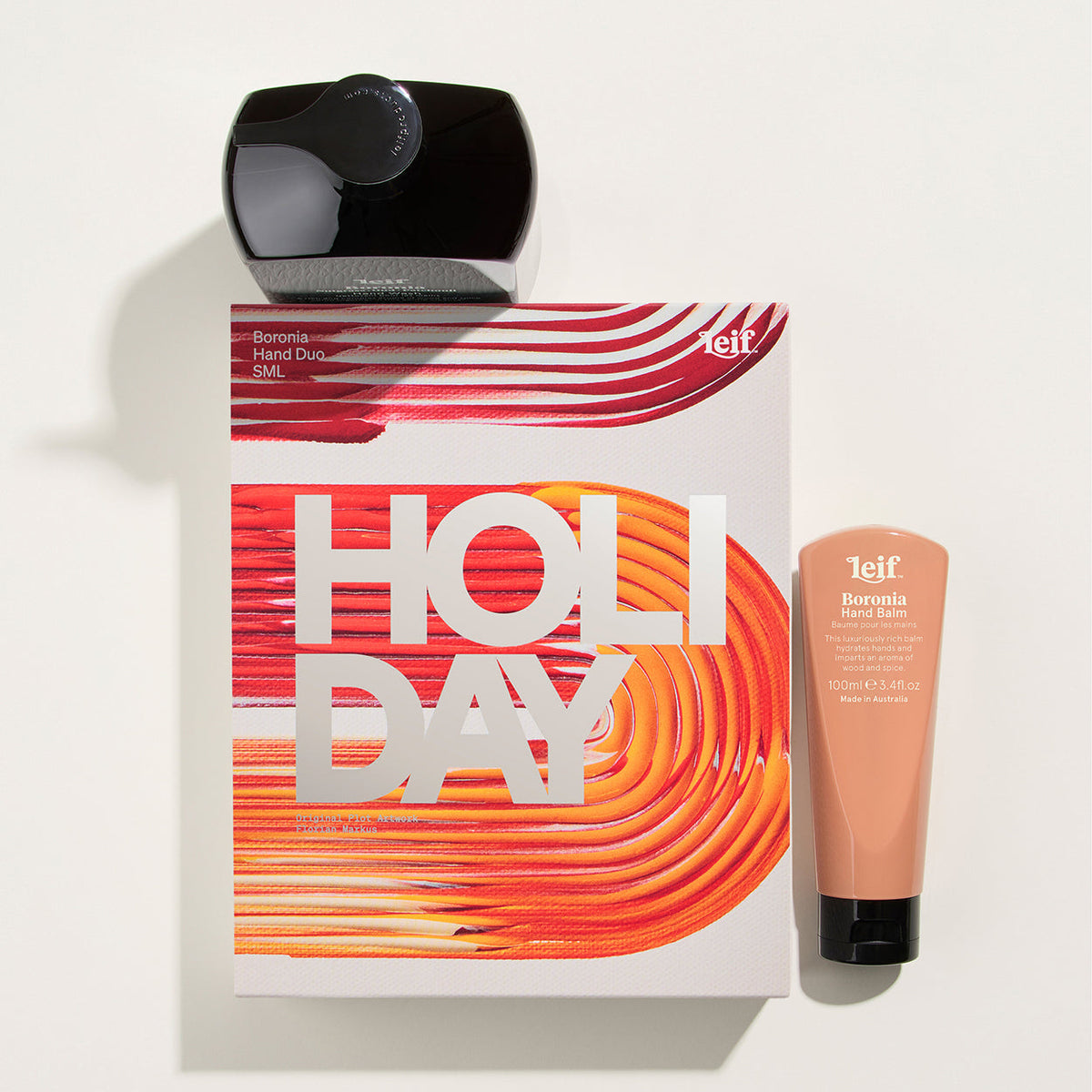 A 1e1f Beauty Box set featuring a black hair dryer, a white and orange 'HOLIDAY' gift box, and a peach-colored body butter tube on a clean white background.
