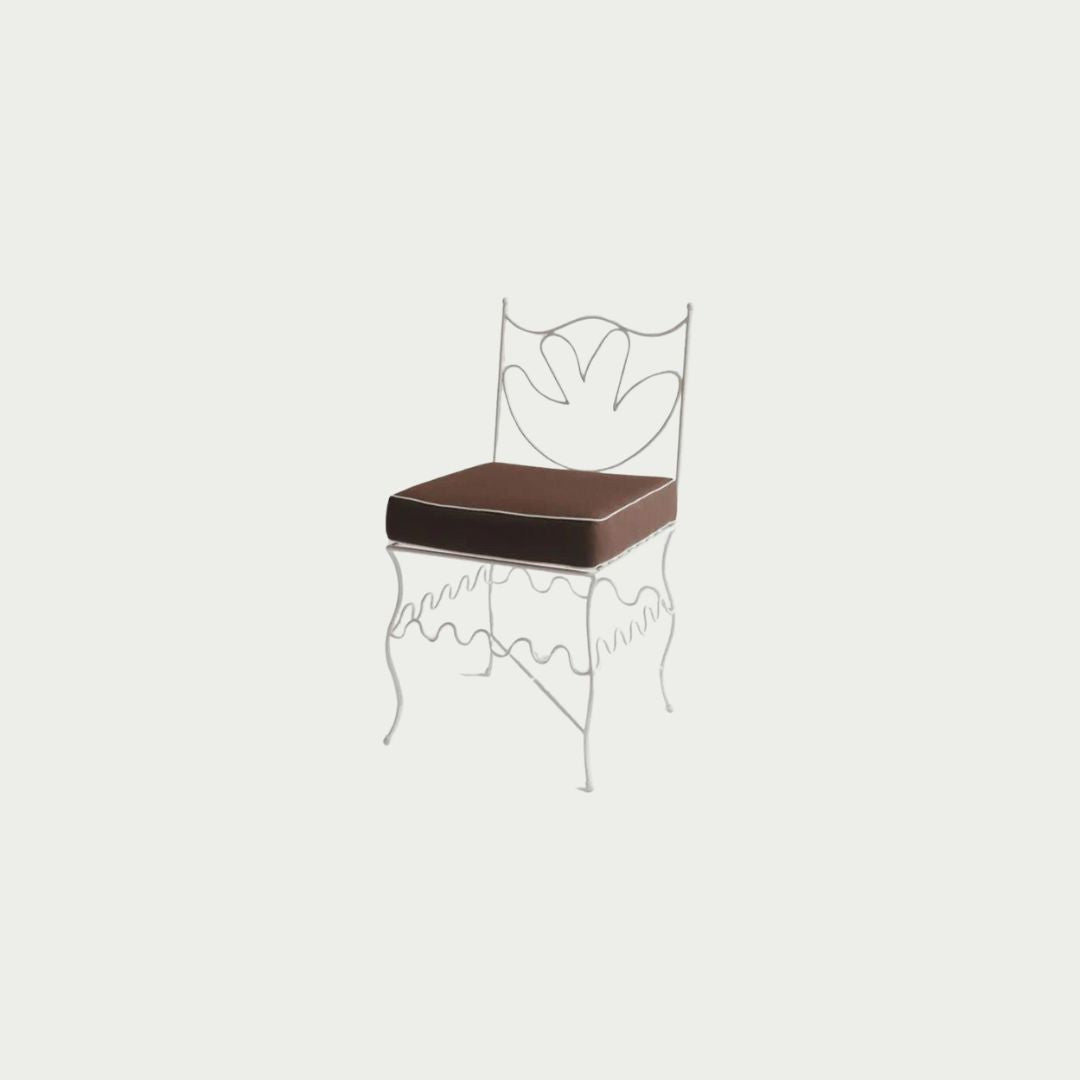 Diego Chair with white iron frame and brown cushion, decorative leaf-motif backrest, styled outdoors.