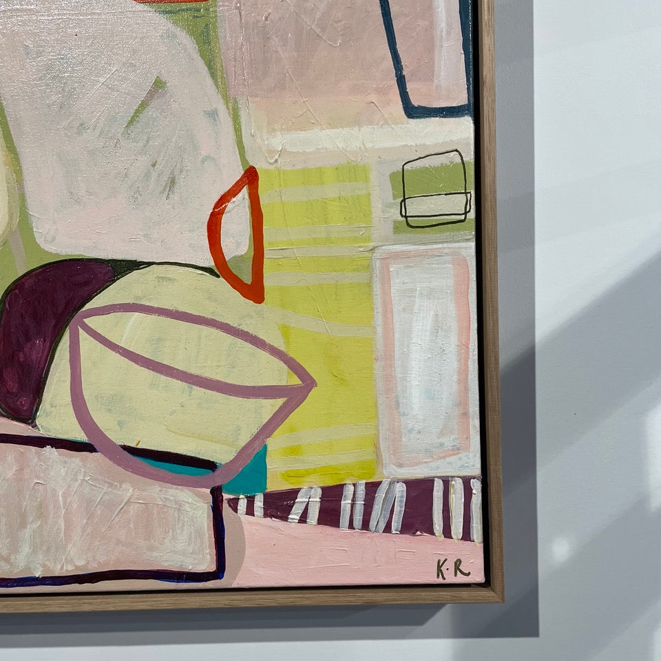 Abstract geometric painting with pastel pink, yellow, green, cream, and burgundy shapes outlined in black, shown in a light wood frame against a white wall.