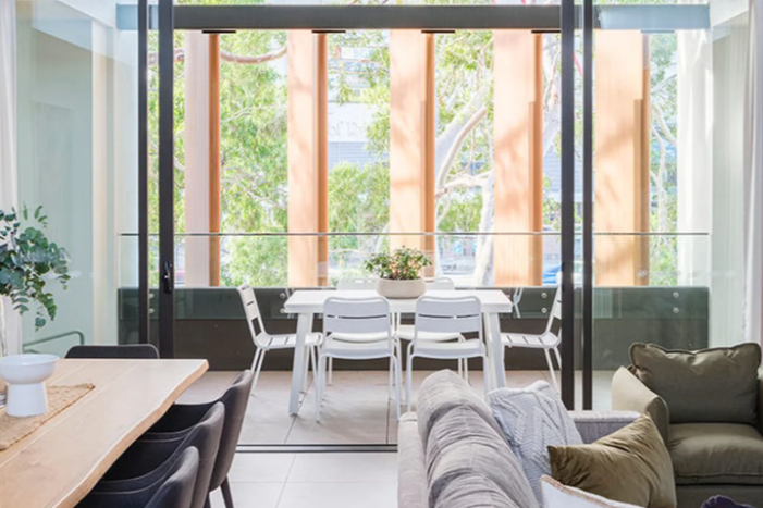 Modern living room with a large window view of trees. Outdoor setting. Outdoor dining set. Stainless steel outdoor dining. 