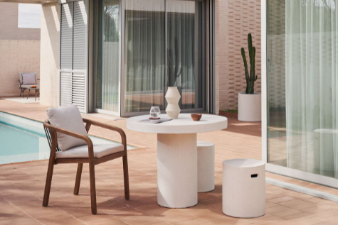 Modern outdoor patio with a table, chairs, and a pool in the background. Concrete table for alfresco dining. outdoor concrete table