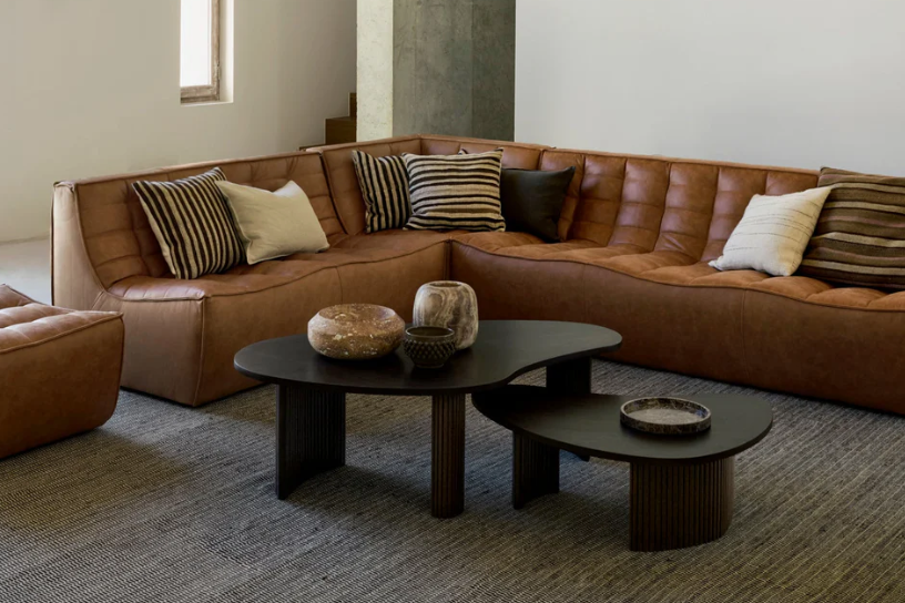Brown leather sectional sofa in a modern living room with a coffee table and decorative items. Modula sofa. leather sofa. 