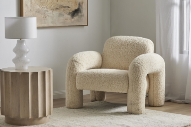 Modern living room with a textured armchair, side table, and abstract painting. Boucle feature chair available in velvet too. Curved armchair. 