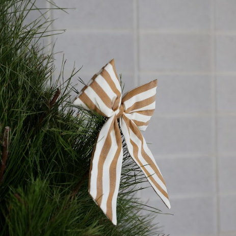 Brown and white striped bow on a green branch against a tiled wall.