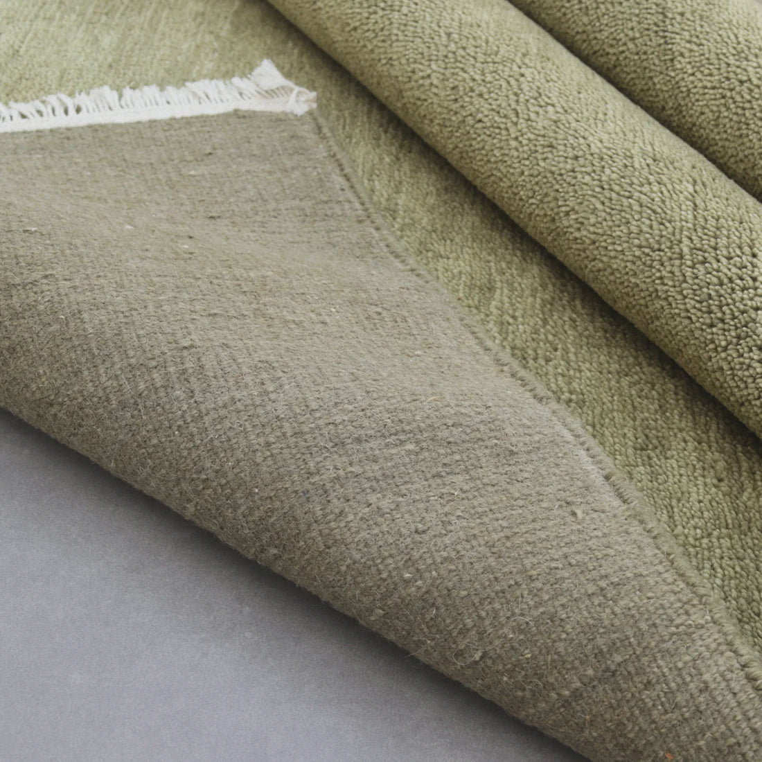 Close-up of green fabric with a textured surface on a gray background