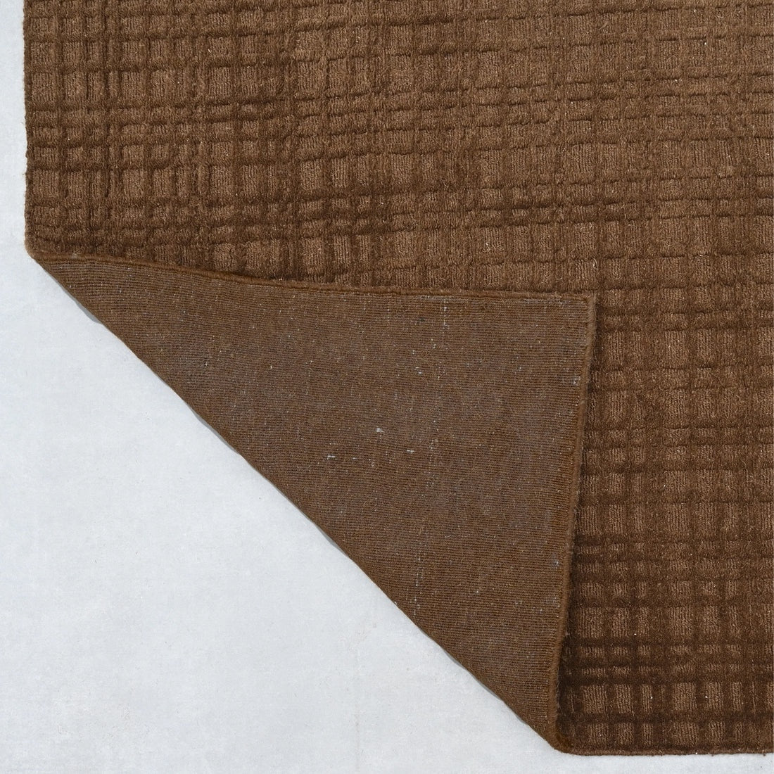 Brown textured rug corner on a white background