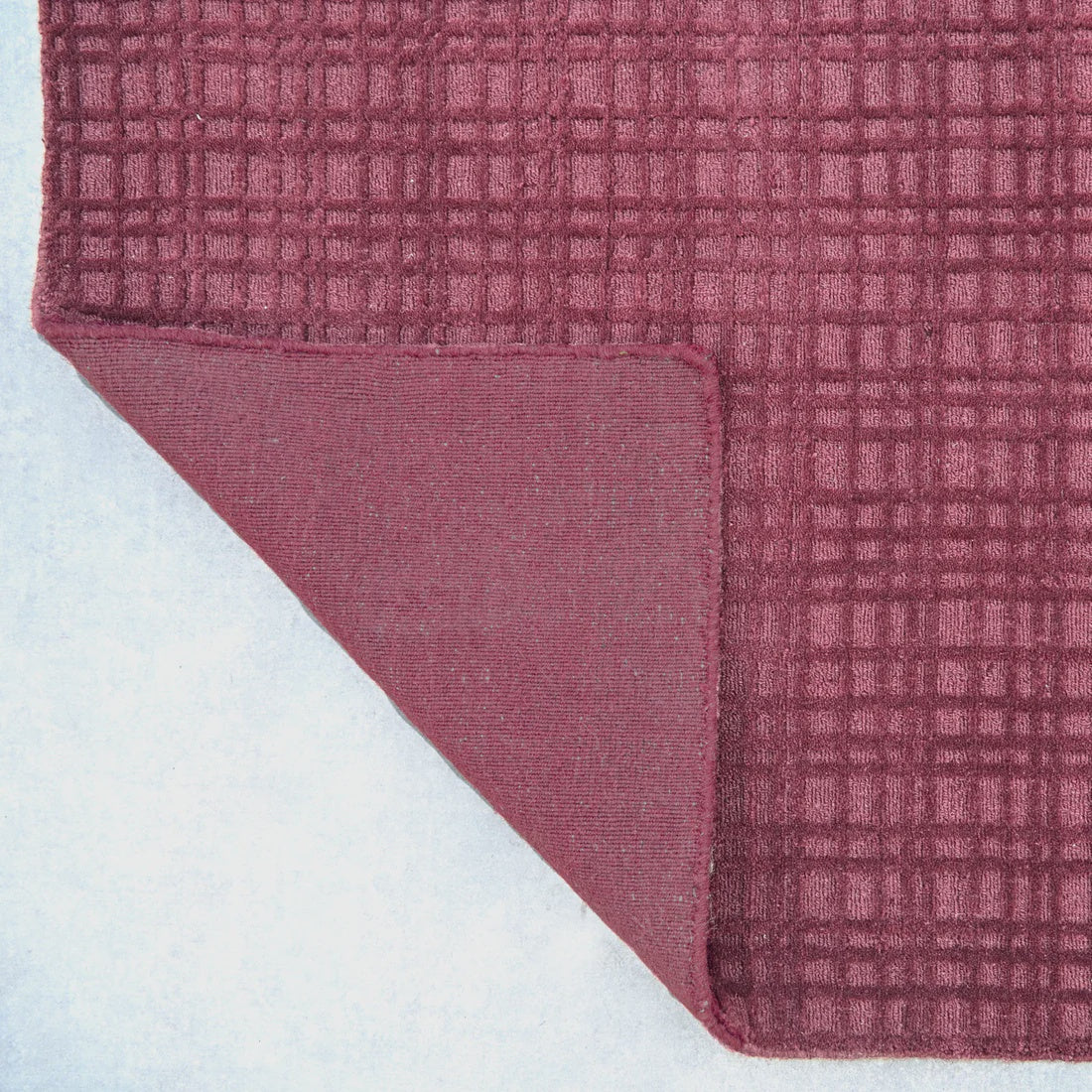 Close-up of a textured pink rug corner on a white background
