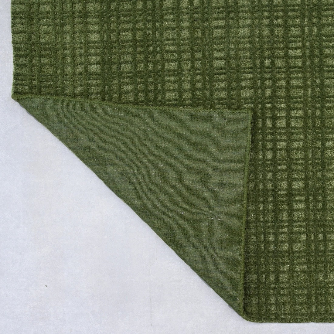 Green textured rug corner on a white background