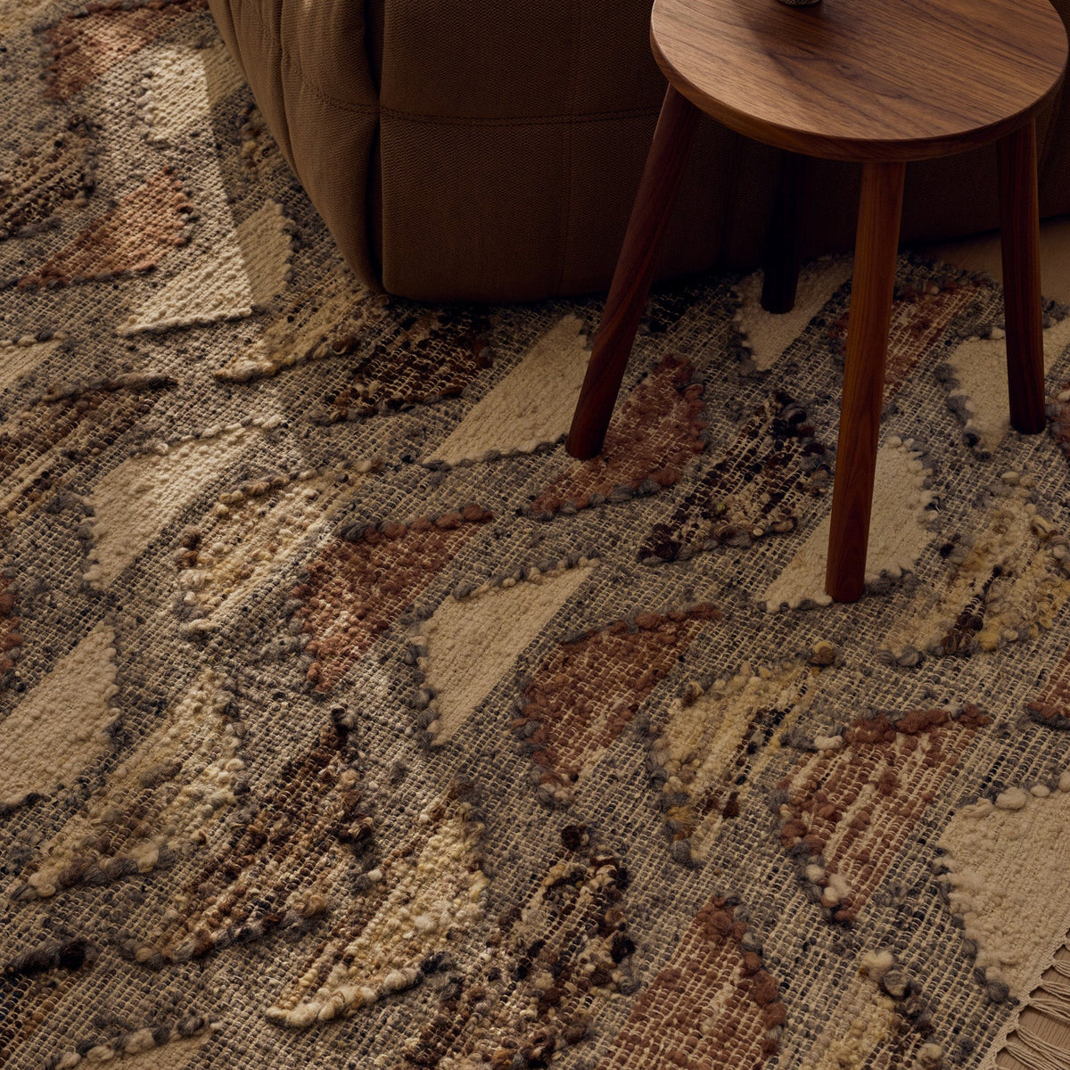 Tribe Home Orissa Rug in wool and jute with rows of rust, sand, brown and cream half-moon shapes on a charcoal grey base with fringed ends