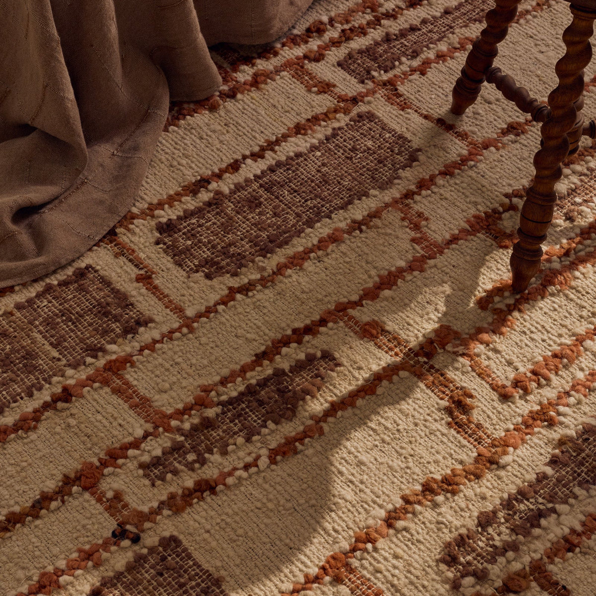 Tribe Home Rama Rug in Sienna with a textured cream base, an irregular charcoal grid pattern, warm sienna filled blocks and fringed ends