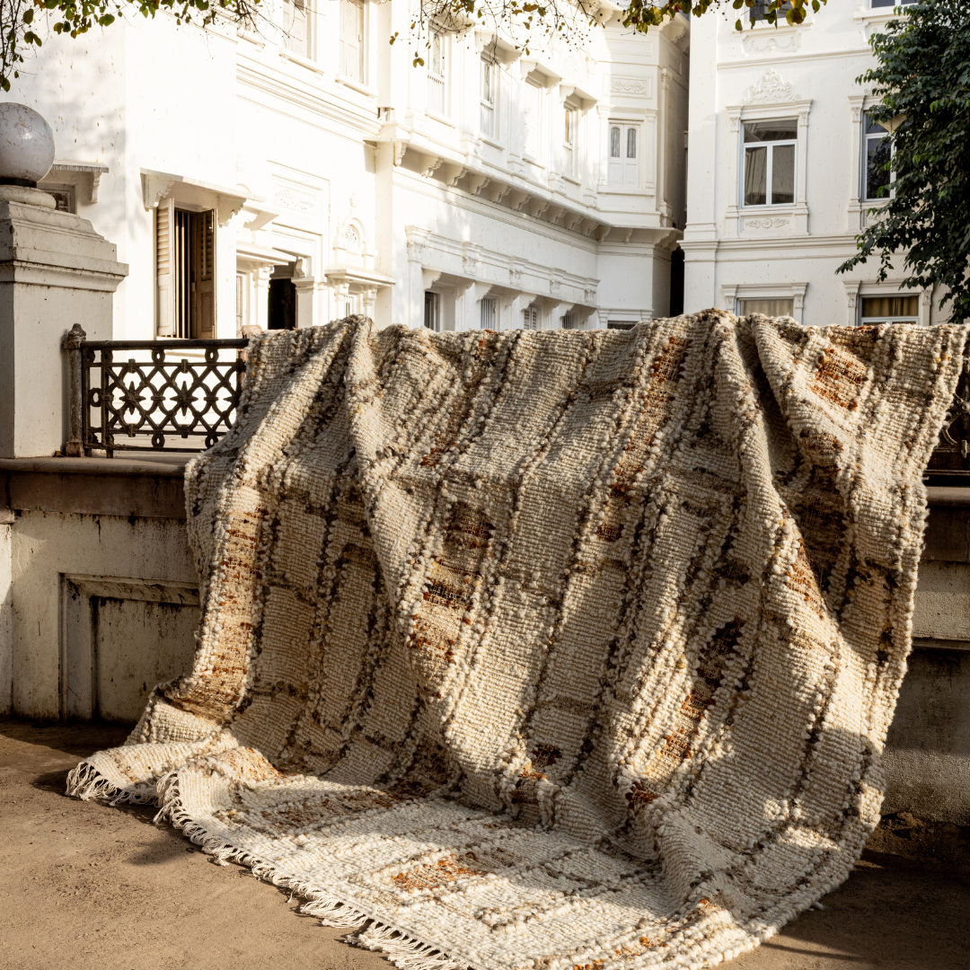 Tribe Home Rama Rug in Cinnamon with a textured cream base, an irregular charcoal grid pattern, cinnamon and rust filled blocks and fringed ends