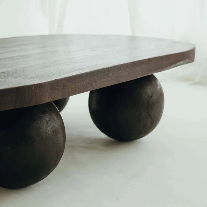 Valentina Table in Walnut suar timber, oval top on four rounded ball legs, shown on a plain studio backdrop.