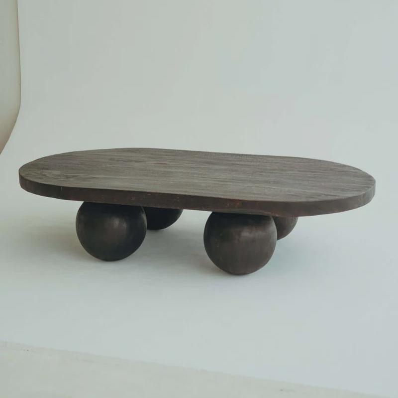 Valentina Table in Walnut suar timber, oval top on four rounded ball legs, shown on a plain studio backdrop.