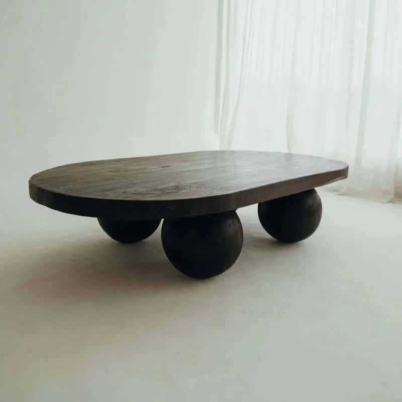 Valentina Table in Walnut suar timber, oval top on four rounded ball legs, shown on a plain studio backdrop.
