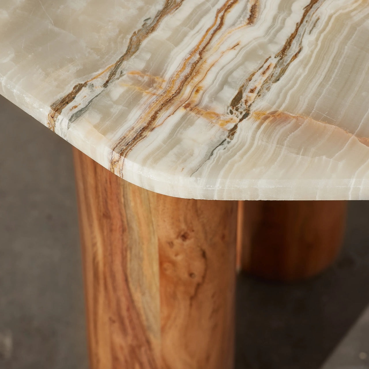 Waverly Side Table in Onyx marble, irregular rounded top on three wooden column legs.