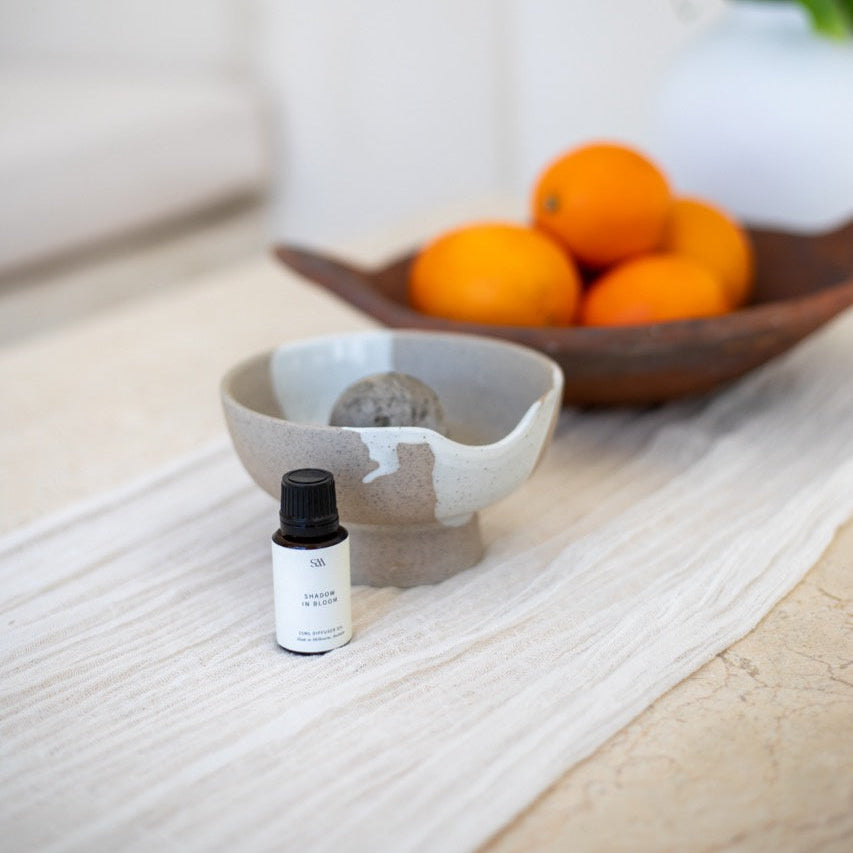 Diffuser with volcanic rock sphere and fragrance oil bottle on styled surface