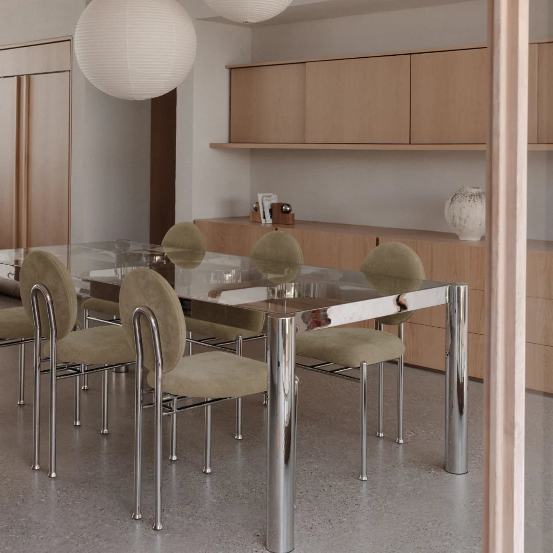 Glass-top dining table with cylindrical stainless steel legs