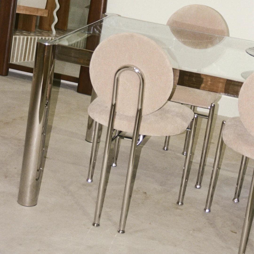 Glass-top dining table with cylindrical stainless steel legs