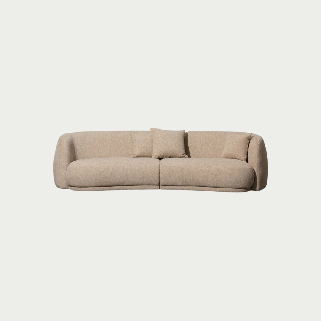 Ziggy Sofa in oatmeal bouclé, rounded pebble-like armrests and curved backrest, styled against a plain wall.