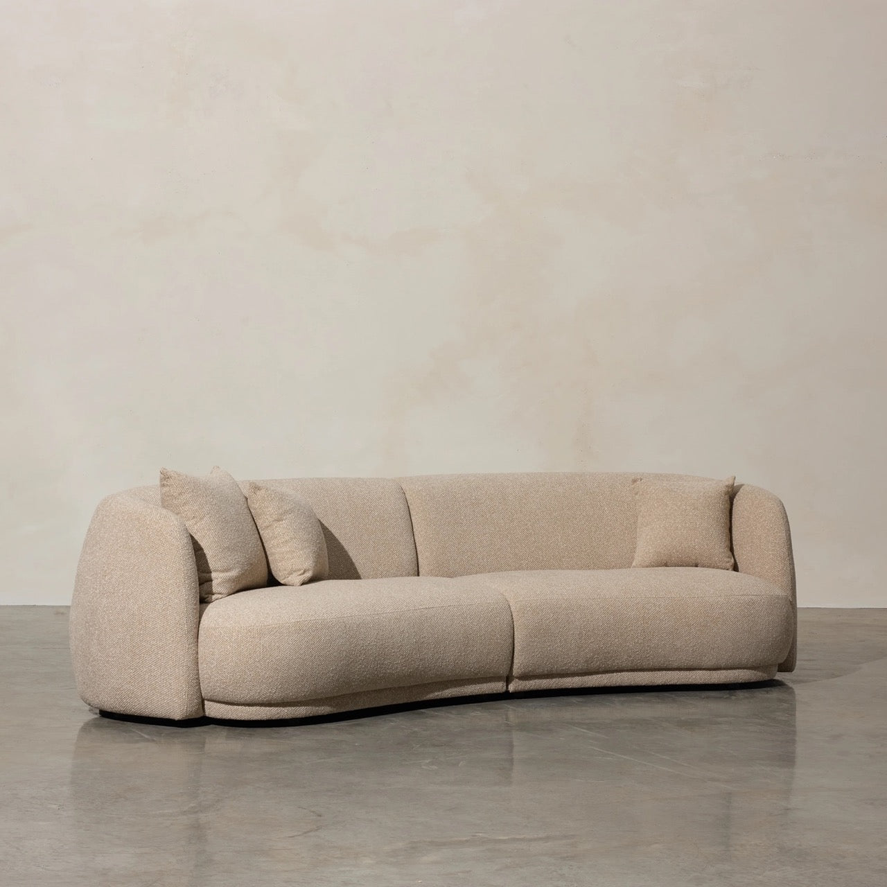 Ziggy Sofa in oatmeal bouclé, rounded pebble-like armrests and curved backrest.