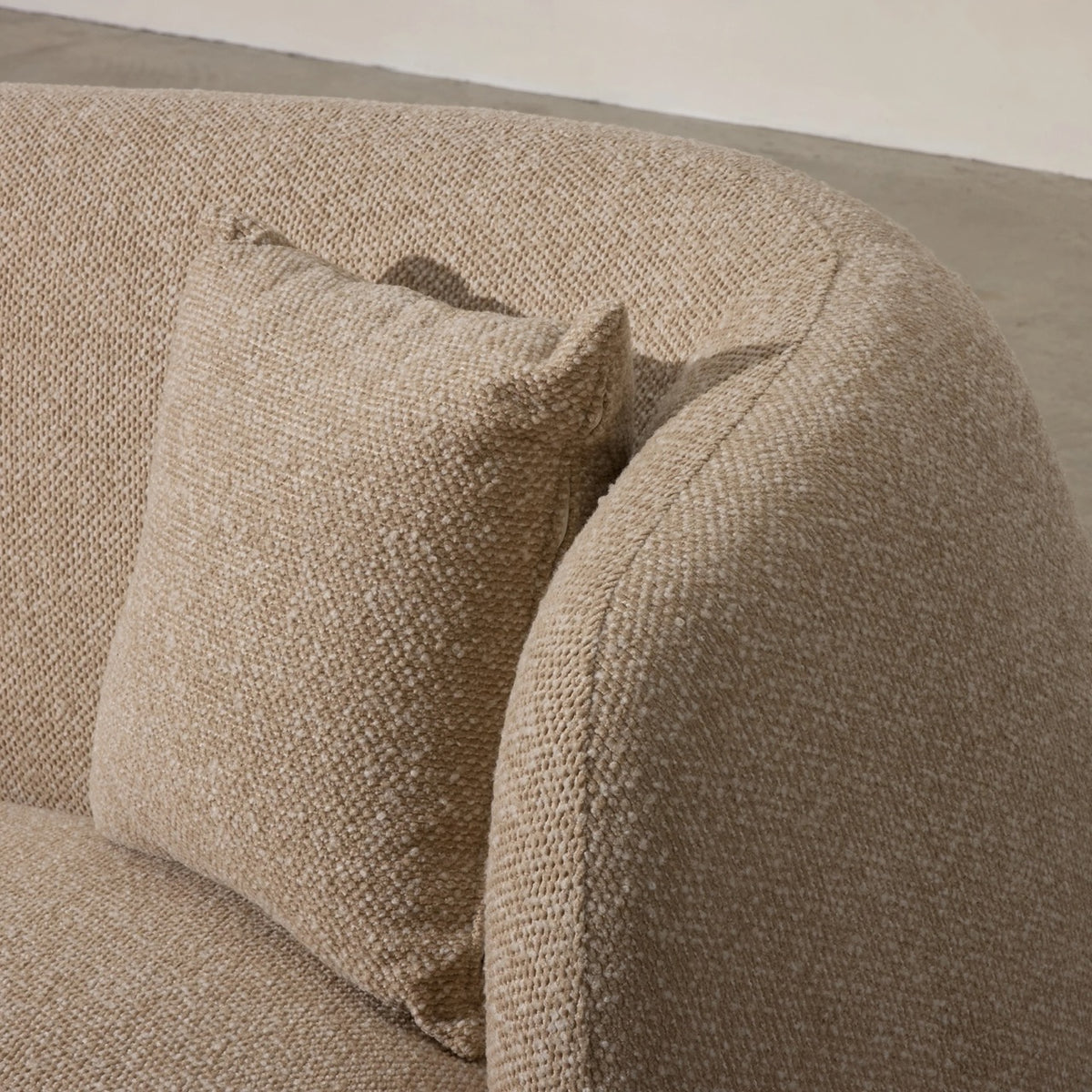 Ziggy Sofa in oatmeal bouclé, rounded pebble-like armrests and curved backrest.