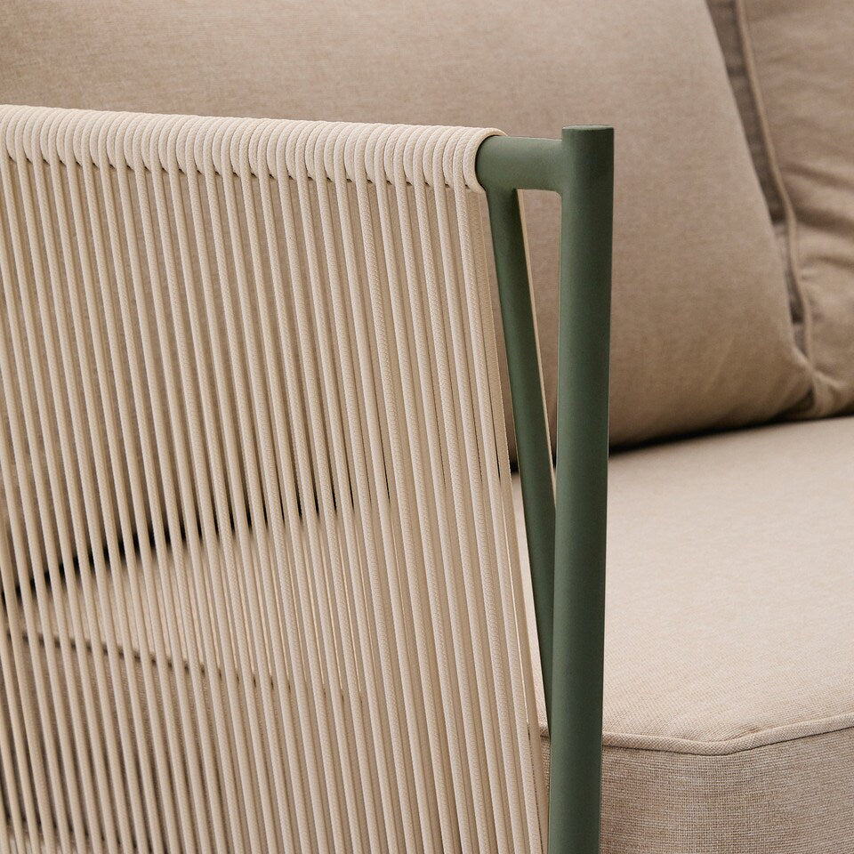 Close-up of a beige outdoor chair with woven design and green metal frame, against a beige sofa background.