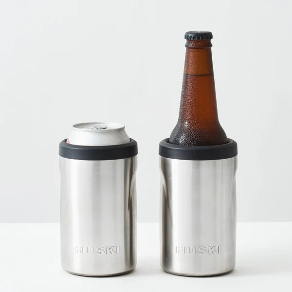 Two stainless steel Huski can coolers, one with a can and the other with a bottle, on a white background.