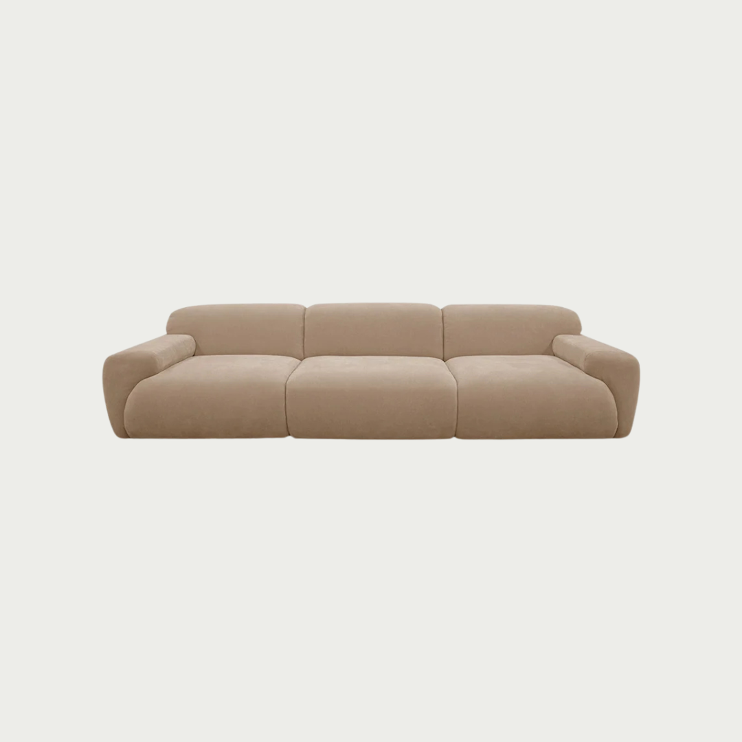 A modern three-seat sofa with a chunky, rounded modular design upholstered in a textured beige fabric, shown against a solid off-white background.