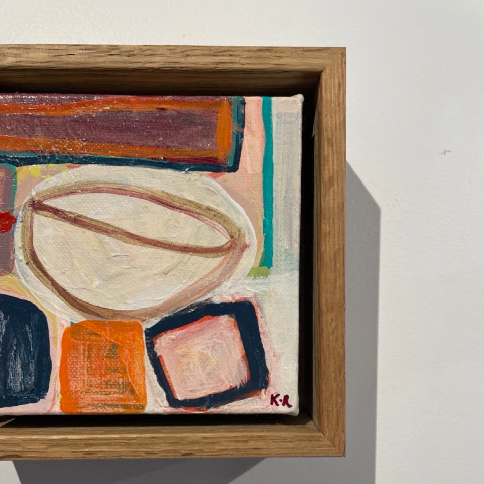 A framed abstract painting with geometric shapes in cream, orange, pink, navy, brown, and teal, mounted on a white wall.